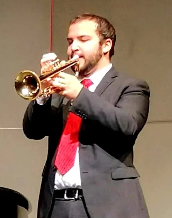 A man in a suit playing a trumpet.